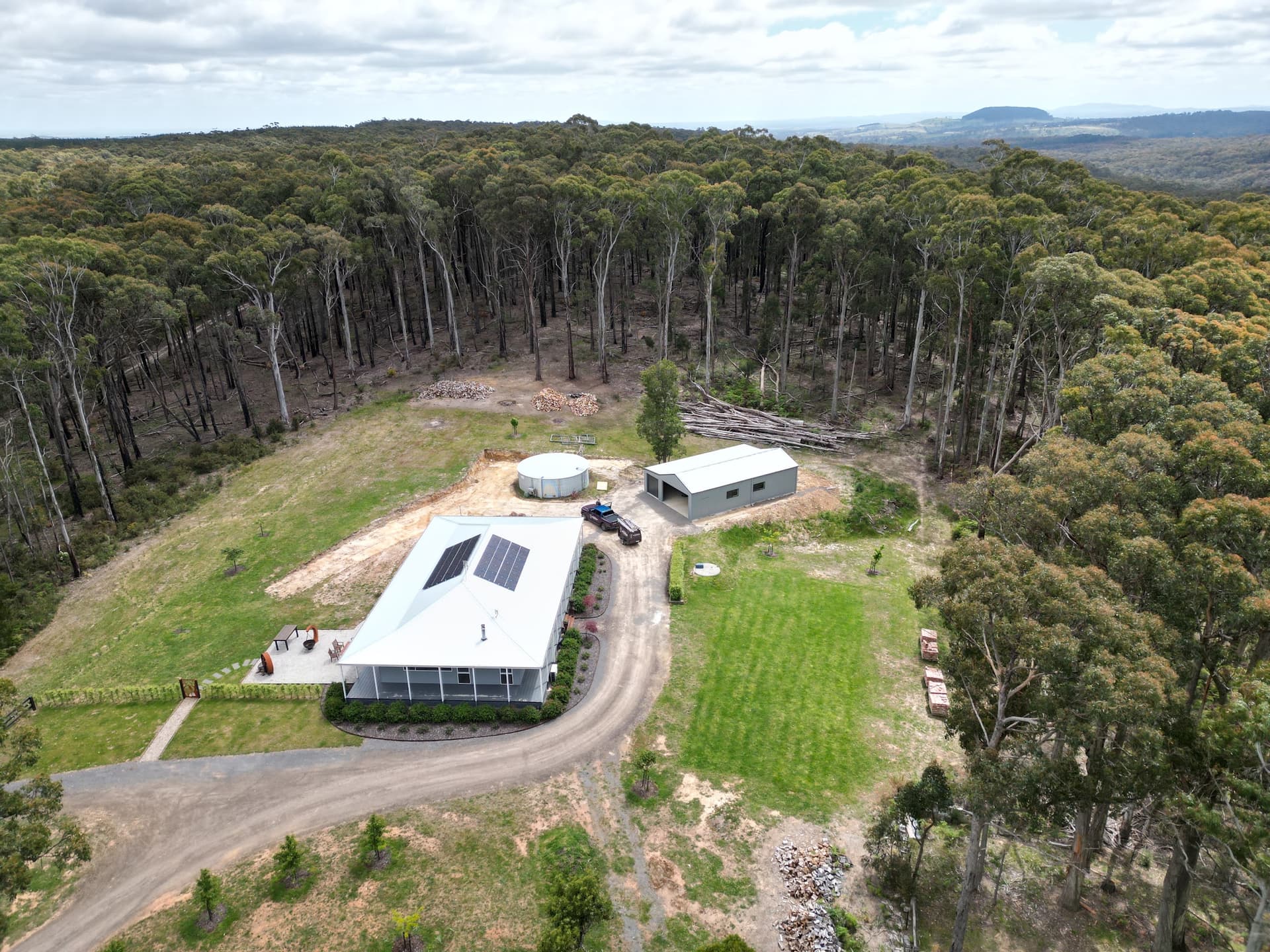A remote property with rooftop solar and shed, ringed by dense forest