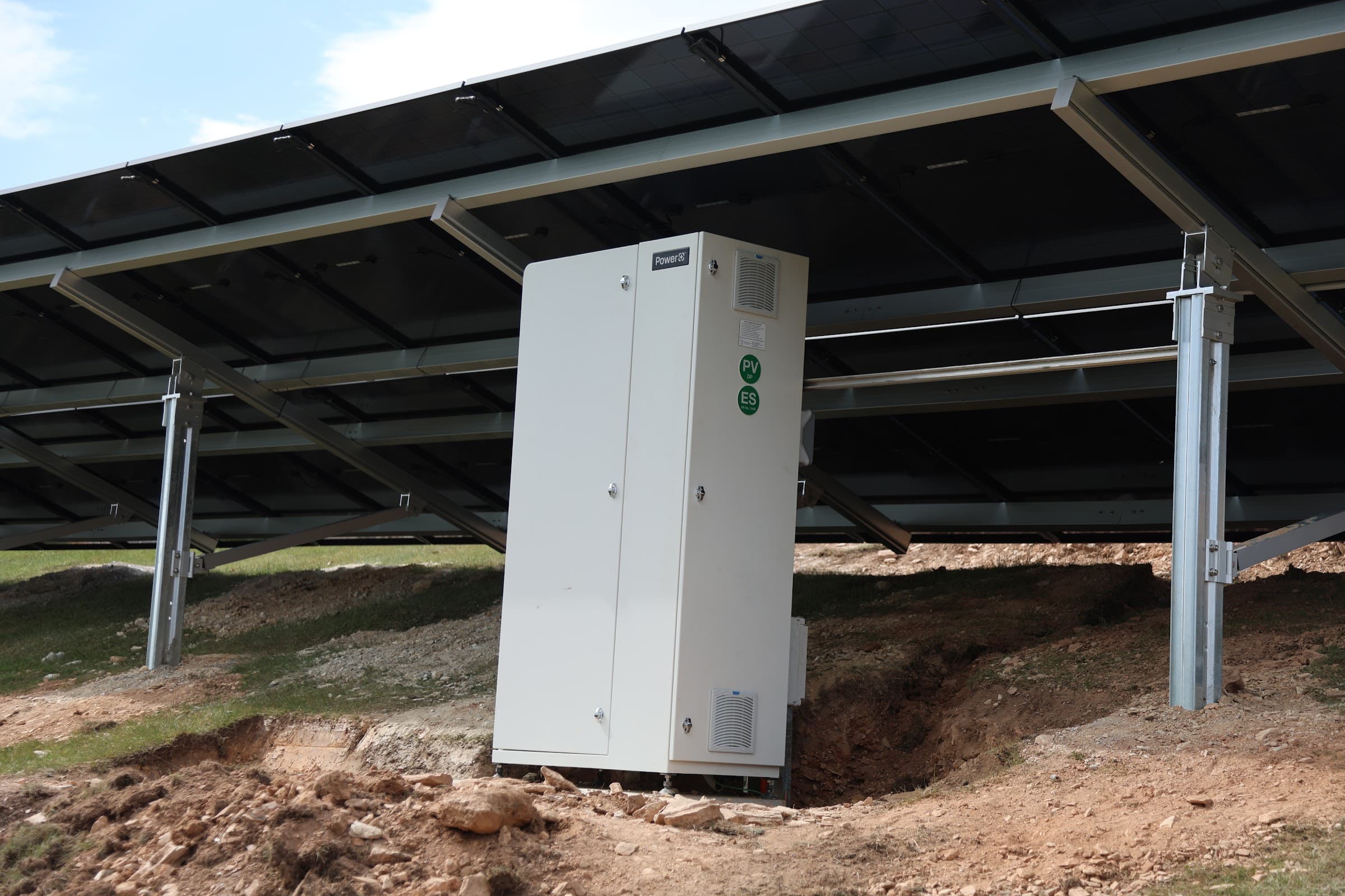 Battery storage cabinet installed beneath the ground-mounted solar array