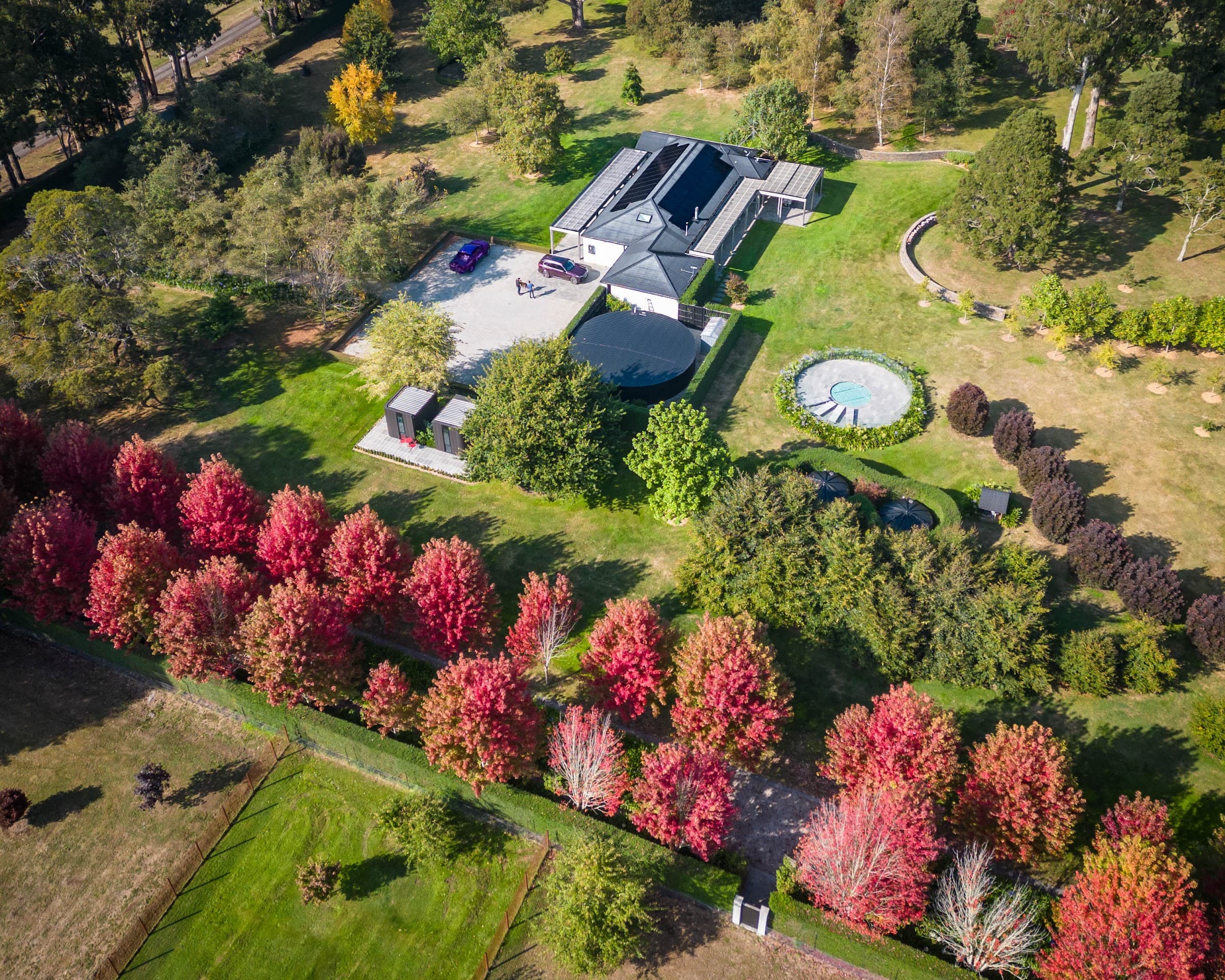 Wide aerial of a solar-equipped estate framed by vivid autumn maples