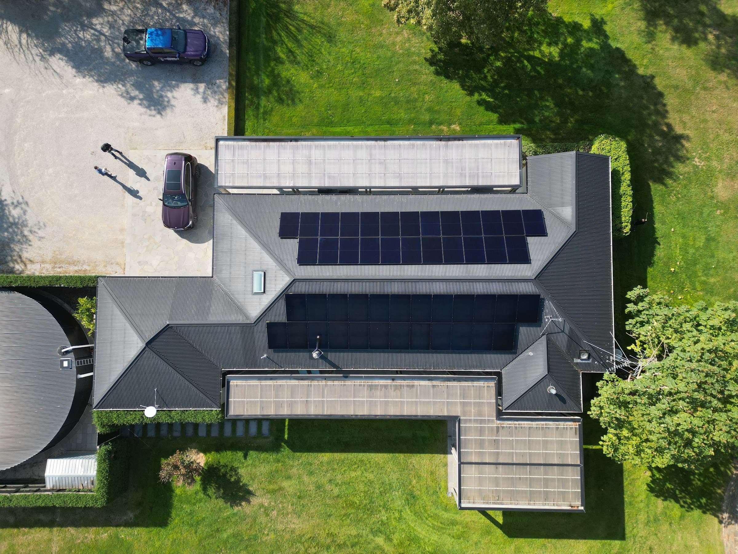 Top-down aerial of a large home at 19 Settlement Road with black solar arrays laid across the whole roofline