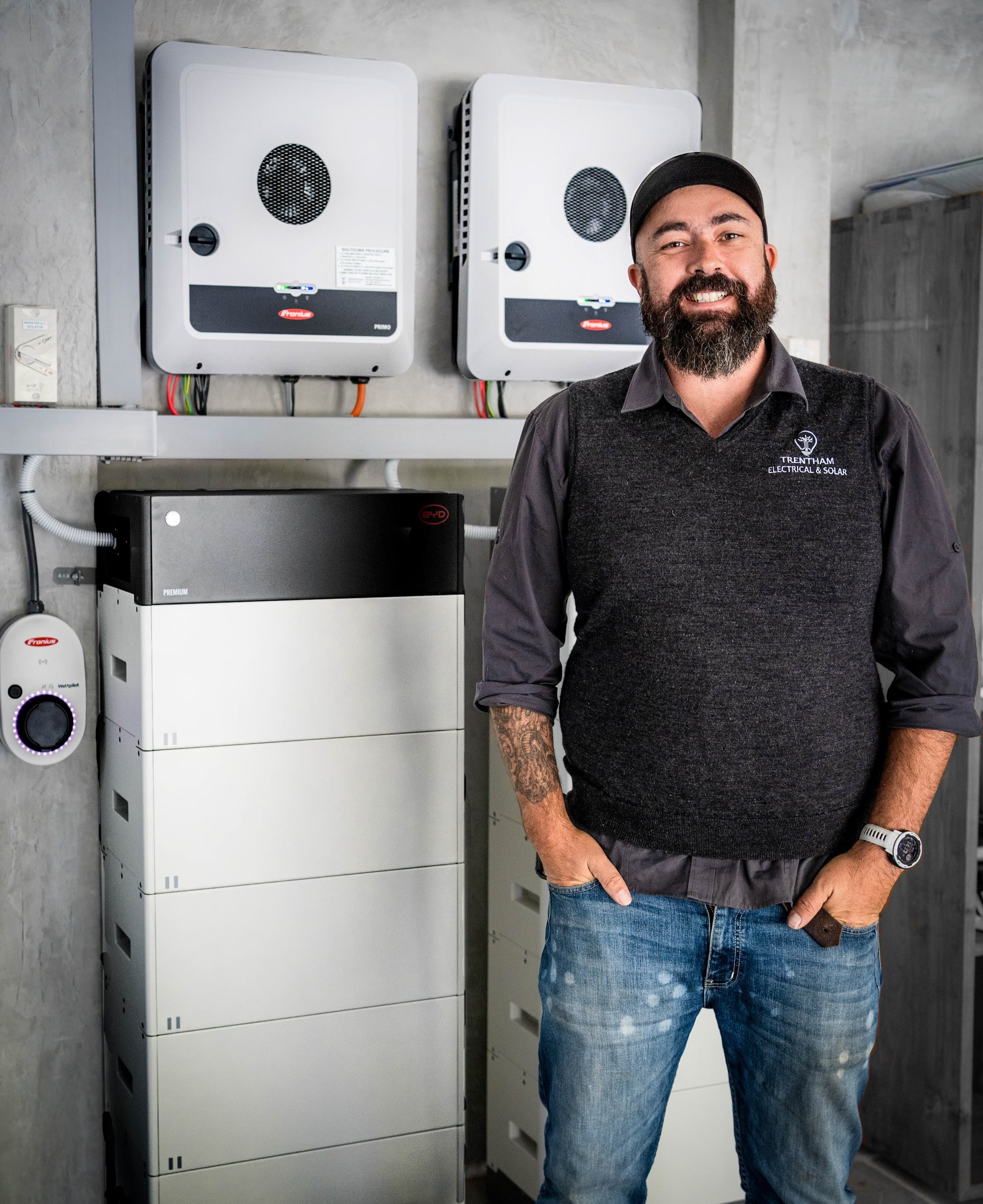 A team member in front of a completed system of inverters, battery storage and an EV charger